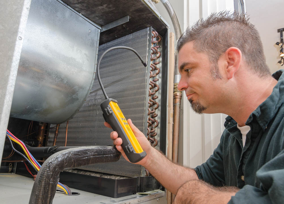 Image of an Hvac technician searching for a refrigerant leak on an evaporator coil.